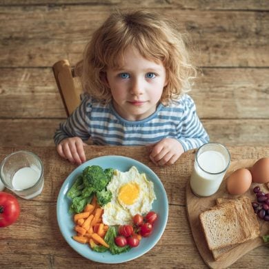This shows a child sitting with a plate of food.