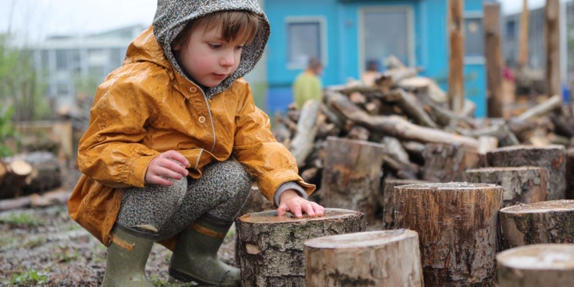 This shows a child playing outside with wooden blocks.