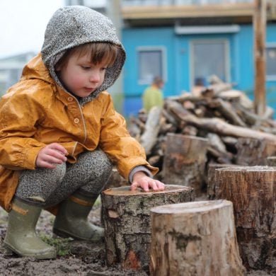 This shows a child playing outside with wooden blocks.