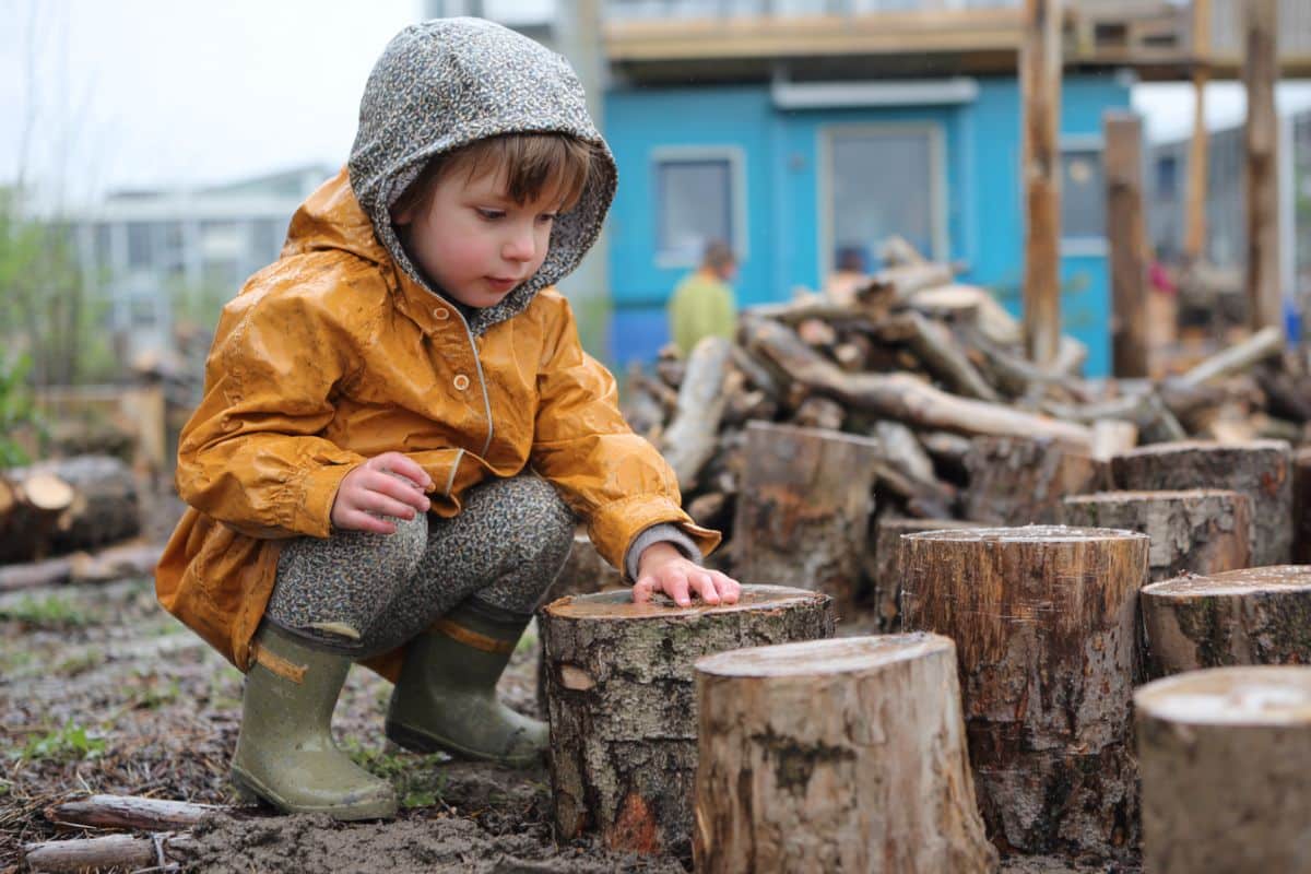 This shows a child playing outside with wooden blocks.