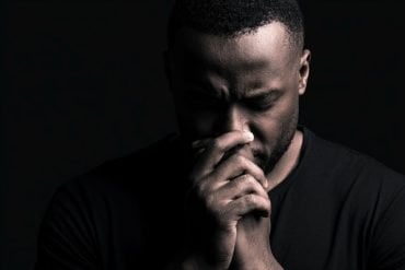 This shows a depressed man with his hands to his nose.