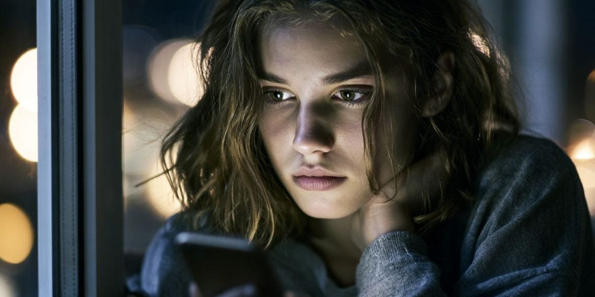 This shows a sad teen on her cell phone.