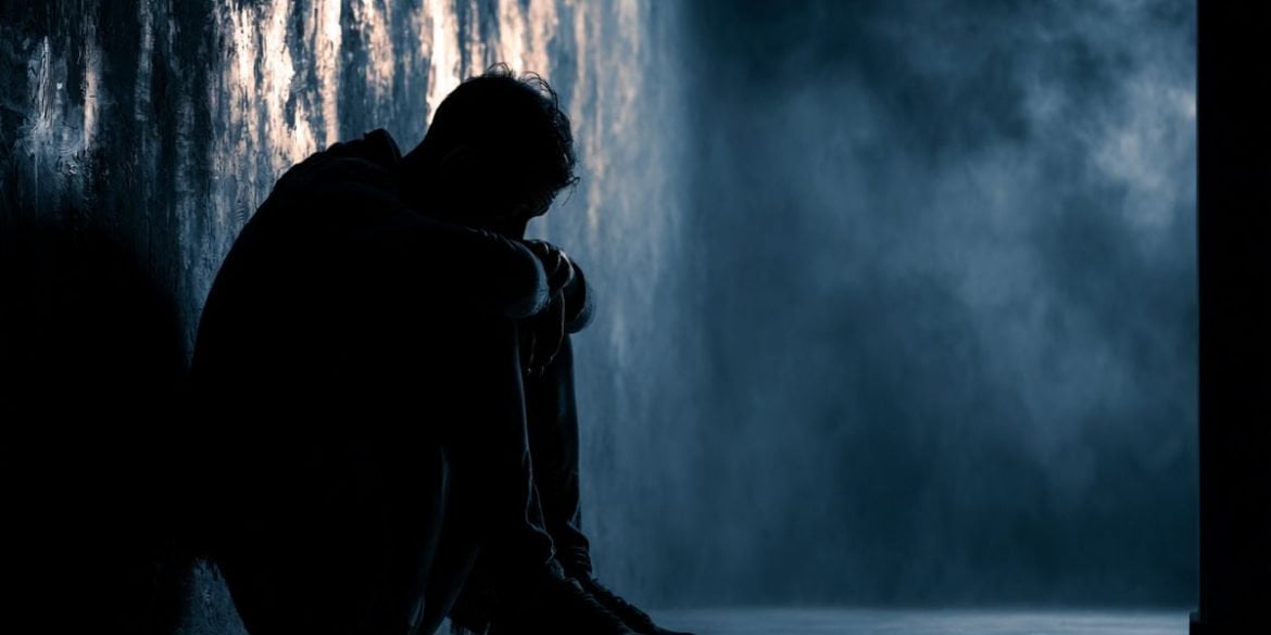 This shows a man sitting against a wall, alone.