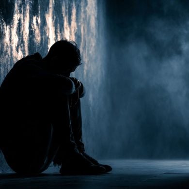 This shows a man sitting against a wall, alone.