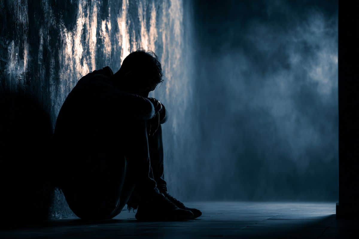 This shows a man sitting against a wall, alone.